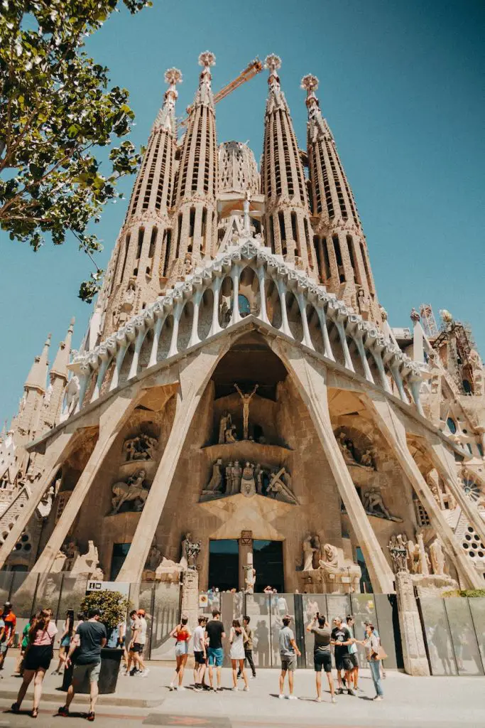 a low angle shot of people walking in front of la sagrada familia